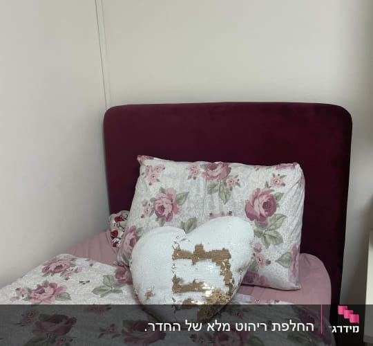 מיטה עם מצעים פרחוניים וכרית לב